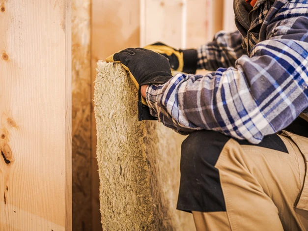 Nicolas Favrin, artisan et fondateur de TY-PEPS, en plein travail sur un chantier de rénovation intérieure, portant des vêtements de professionnel du bâtiment, concentré lors d'une intervention d'électricité, plomberie ou plaquisterie dans une pièce en cours de rénovation, photographie professionnelle authentique et engageante.